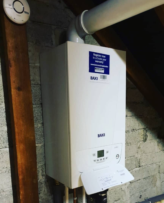 Baxi combi boiler fitted on an attic wall with flue pipe and controls
