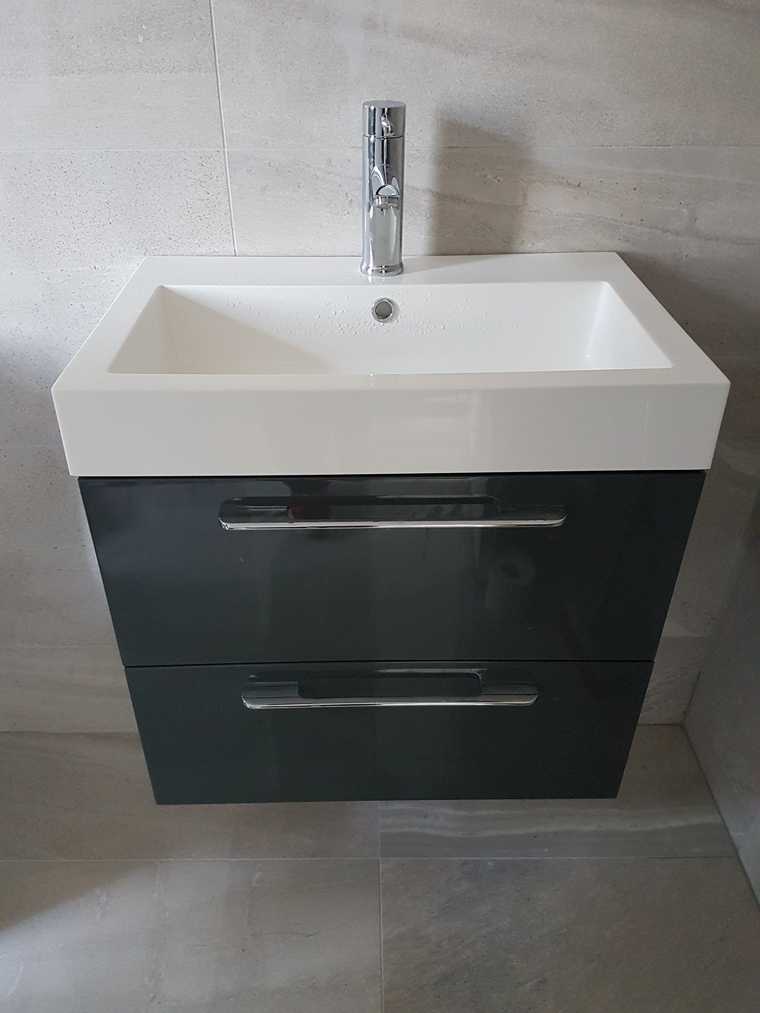 Wall-hung vanity basin with a chrome mixer tap in a tiled bathroom
