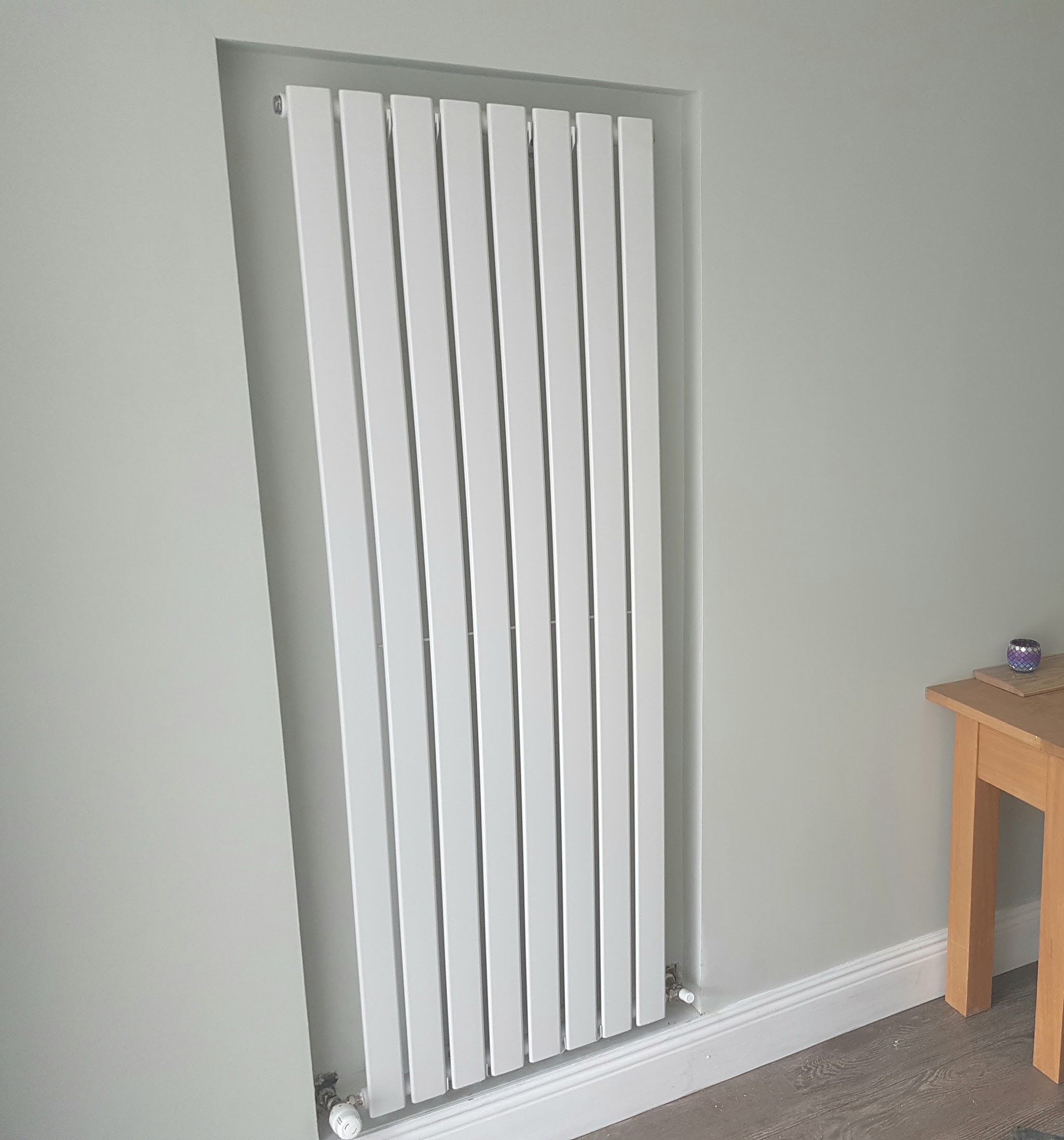 Tall white panel radiator fitted into a wall recess